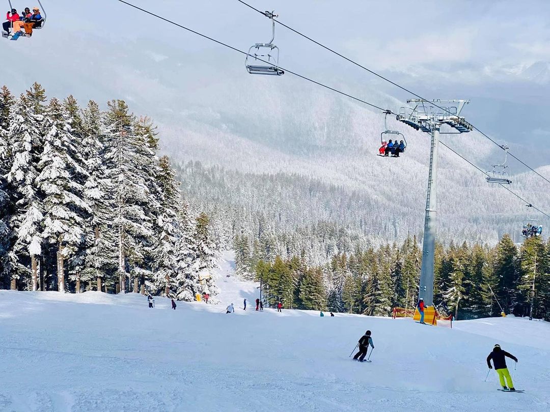 Skiers descend below the chair lift line