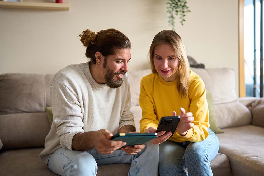 Comparing living costs between Bulgaria and Finland Couple comfortably comparing living costs between Bulgaria and Finland using tablet for family budget analysis