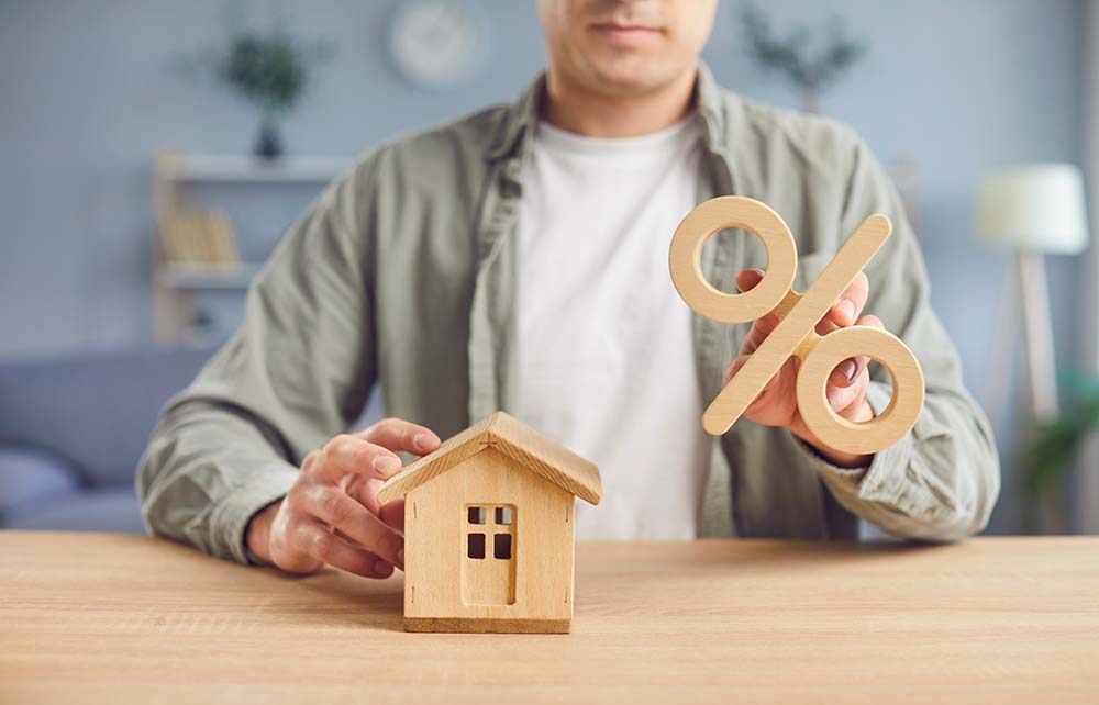 Explaining mortgage terms for Finnish property buyers Person holding wooden house model and percentage symbol explaining mortgage terms for Finnish property buyers
