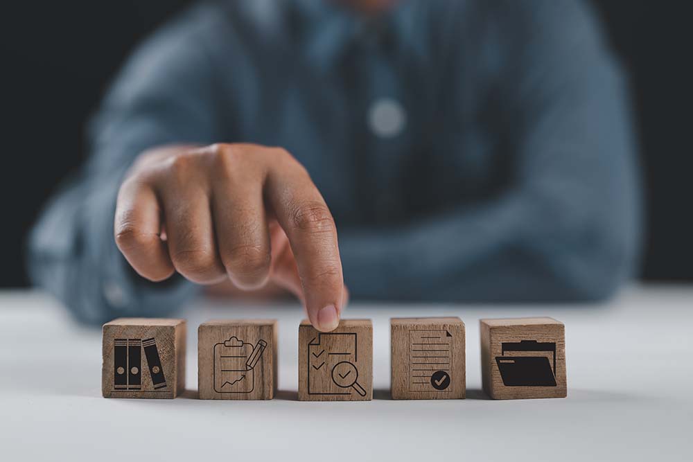 Selecting key property verification steps Hand pointing to wooden blocks with property icons representing essential pre-purchase verification steps for buyers