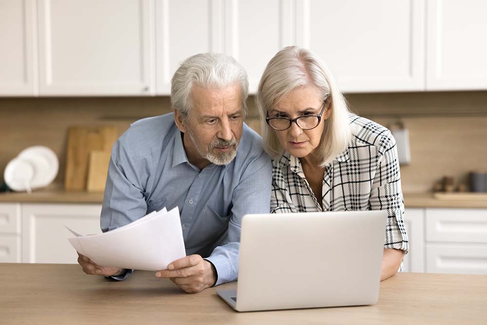 Learning to avoid common property purchase mistakes Finnish mature couple carefully studying common property pu...se mistakes and prevention strategies using laptop and documents