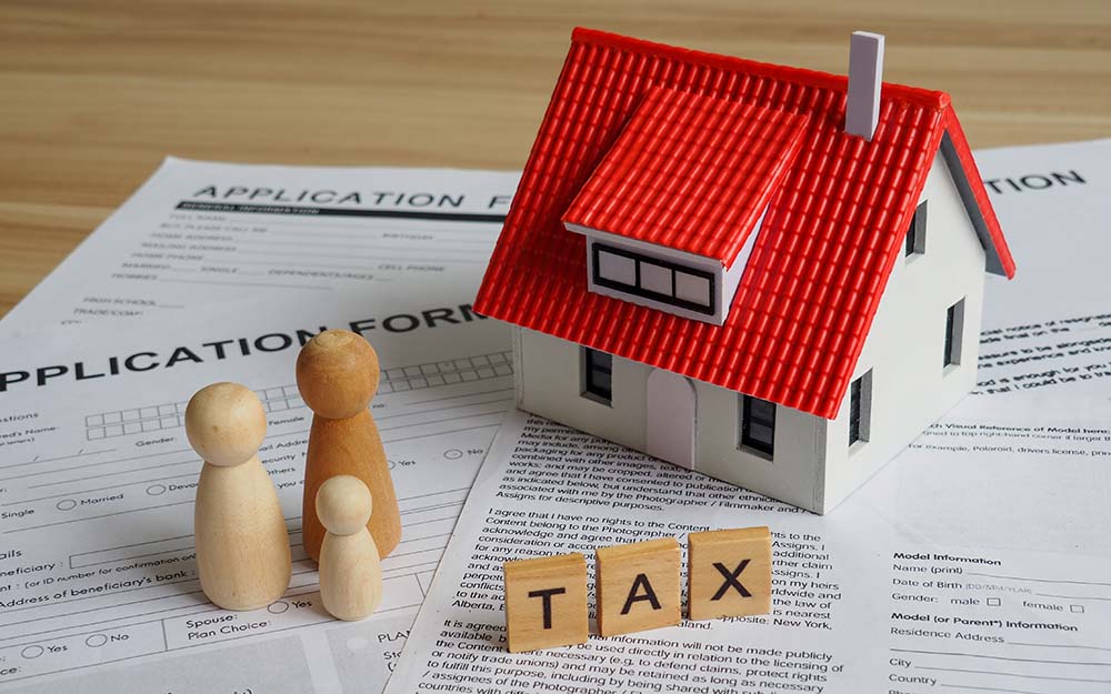 Property sale taxation optimization for EU citizens Red-roofed house model with TAX wooden blocks and documents illustrating property sale taxation optimization for EU citizens