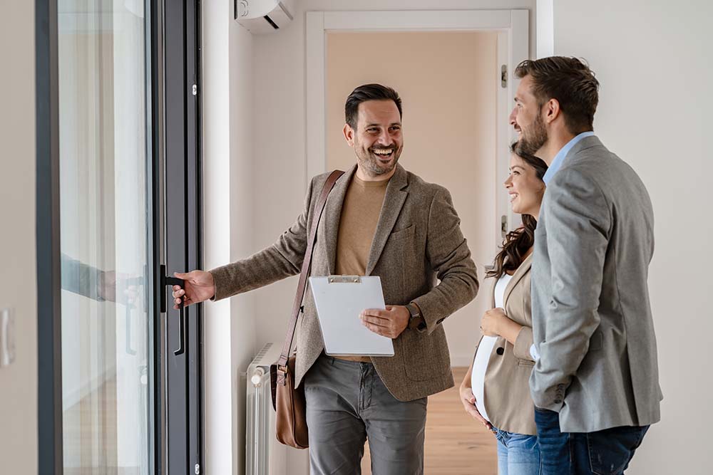 Irish buyers completing successful apartment purchase in Bulgaria Irish property buyers celebrating successful apartment purchase completion with Bulgarian real estate agent during final walkthrough in empty new home