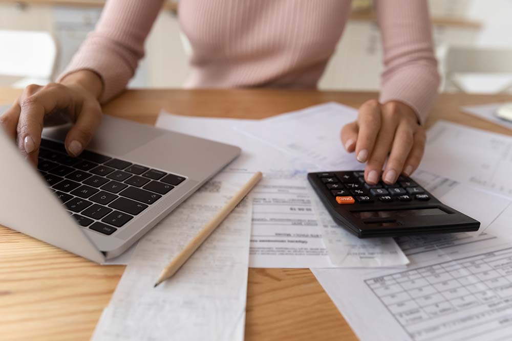 Irish buyer calculating transaction expenses before purchase Irish woman calculating all possible transaction expenses at home using laptop and calculator before property purchase in Bulgaria