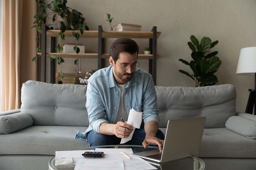 Irish owner calculating annual property expenses in Bulgaria Irish property owner calculating annual ownership expenses including Bulgarian specific «taxa support» fees at home using laptop and documents
