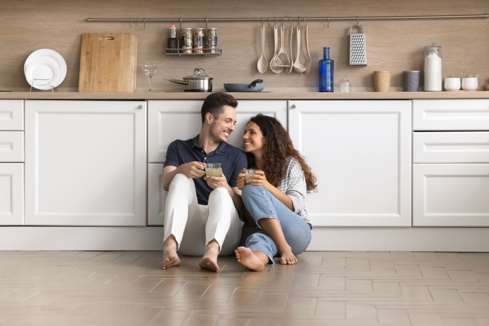 A young couple sits on the floor of a new kitchen, reflecting the comfort of expat residence and integration in Bulgaria