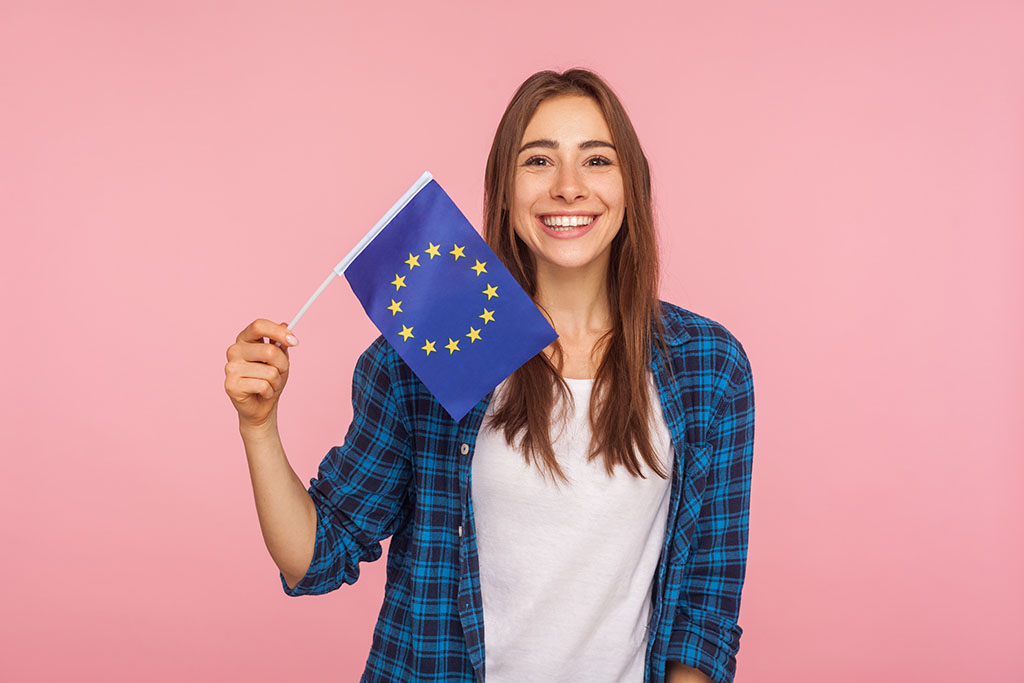 A smiling woman holds the EU flag, pointing to the rights of EU citizens to buy land in Bulgaria