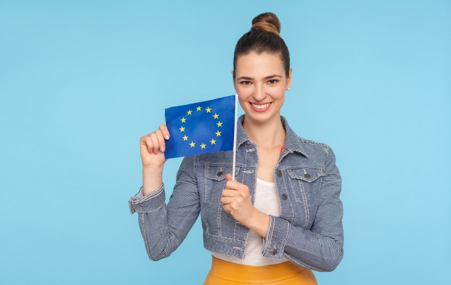 A smiling woman holds the EU flag, confirming the legal rights of Belgian citizens to property in Bulgaria.
