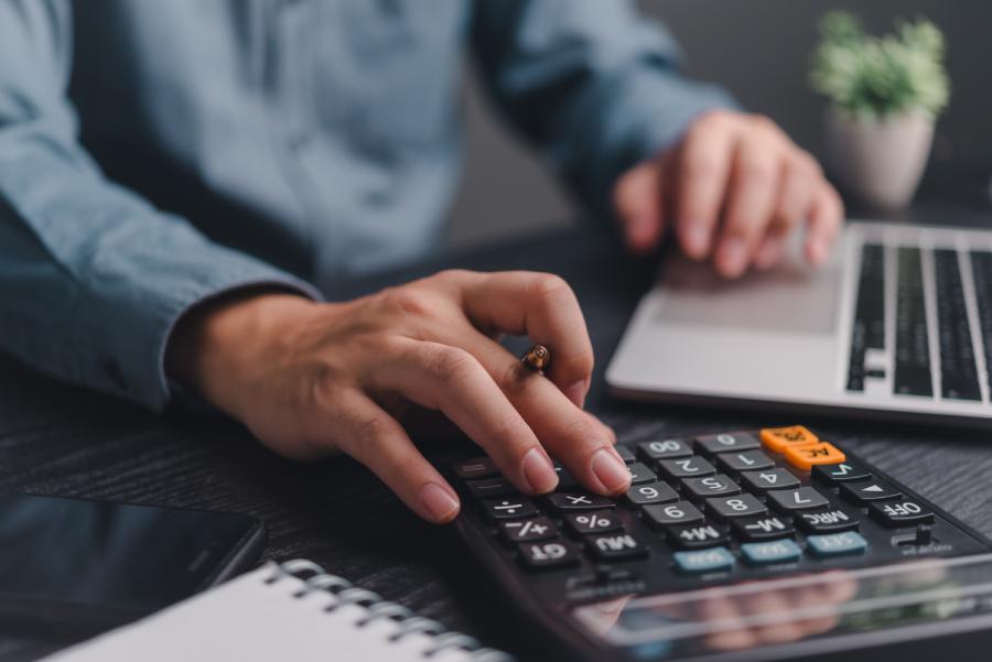 Close-up of hands using a calculator and laptop to conduct a tax analysis Belgium – Bulgaria.