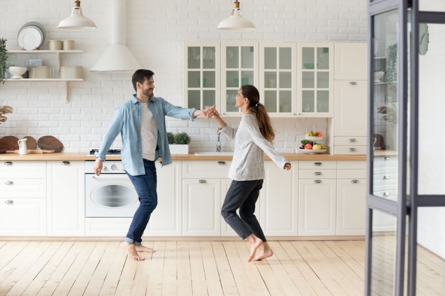 A young couple dances barefoot in a bright kitchen, reflecting the simplicity of residence and residency in Bulgaria.