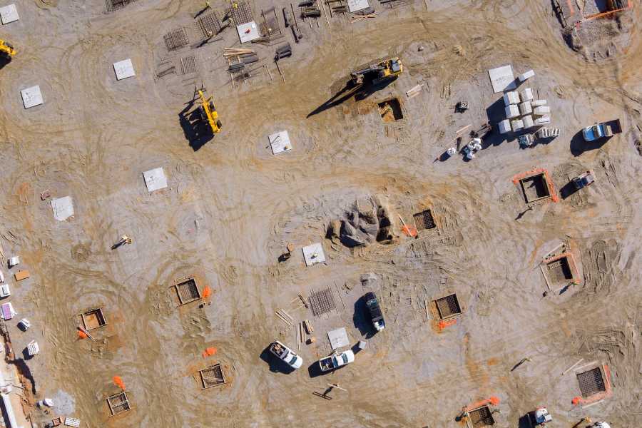 Top view of a construction site with machinery illustrates risks and savings when buying an apartment at the foundation stage in Bulgaria.