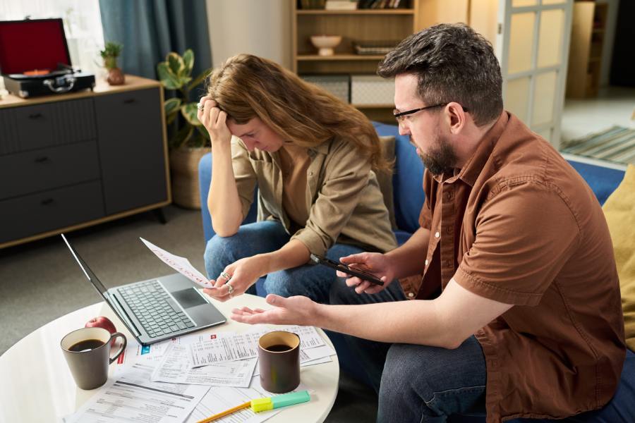 Distressed couple studies documents and laptop, regretting a mistake made when buying property at the foundation stage in Bulgaria.