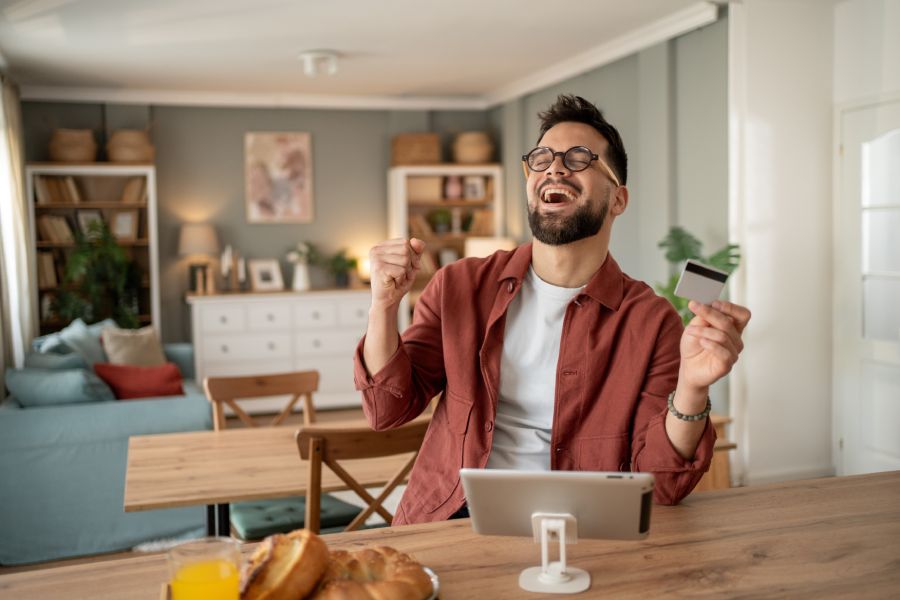 Happy man with bank card celebrates profit from property investment at the foundation stage in Bulgaria.